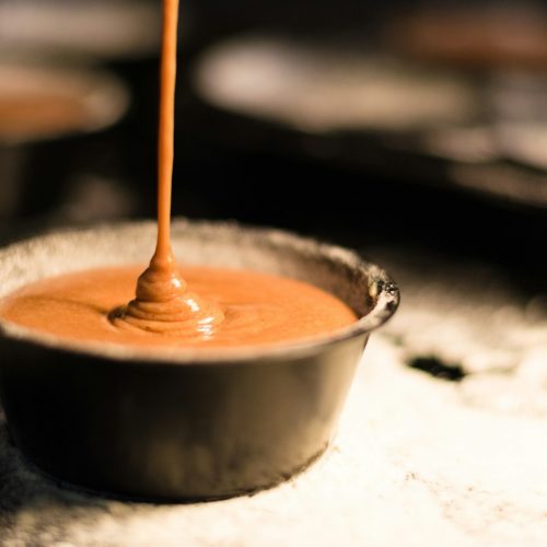 Doce de leite cremoso escorrendo de uma colher para a panela