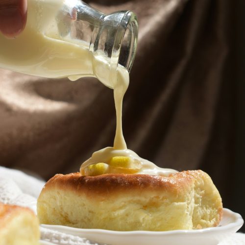 Leite condensado caseiro sendo despejado de uma garrafinha sobre um pão