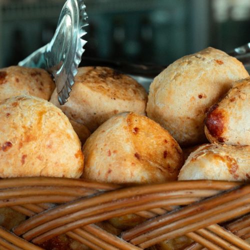 Pães de queijo dourados numa cesta de vime